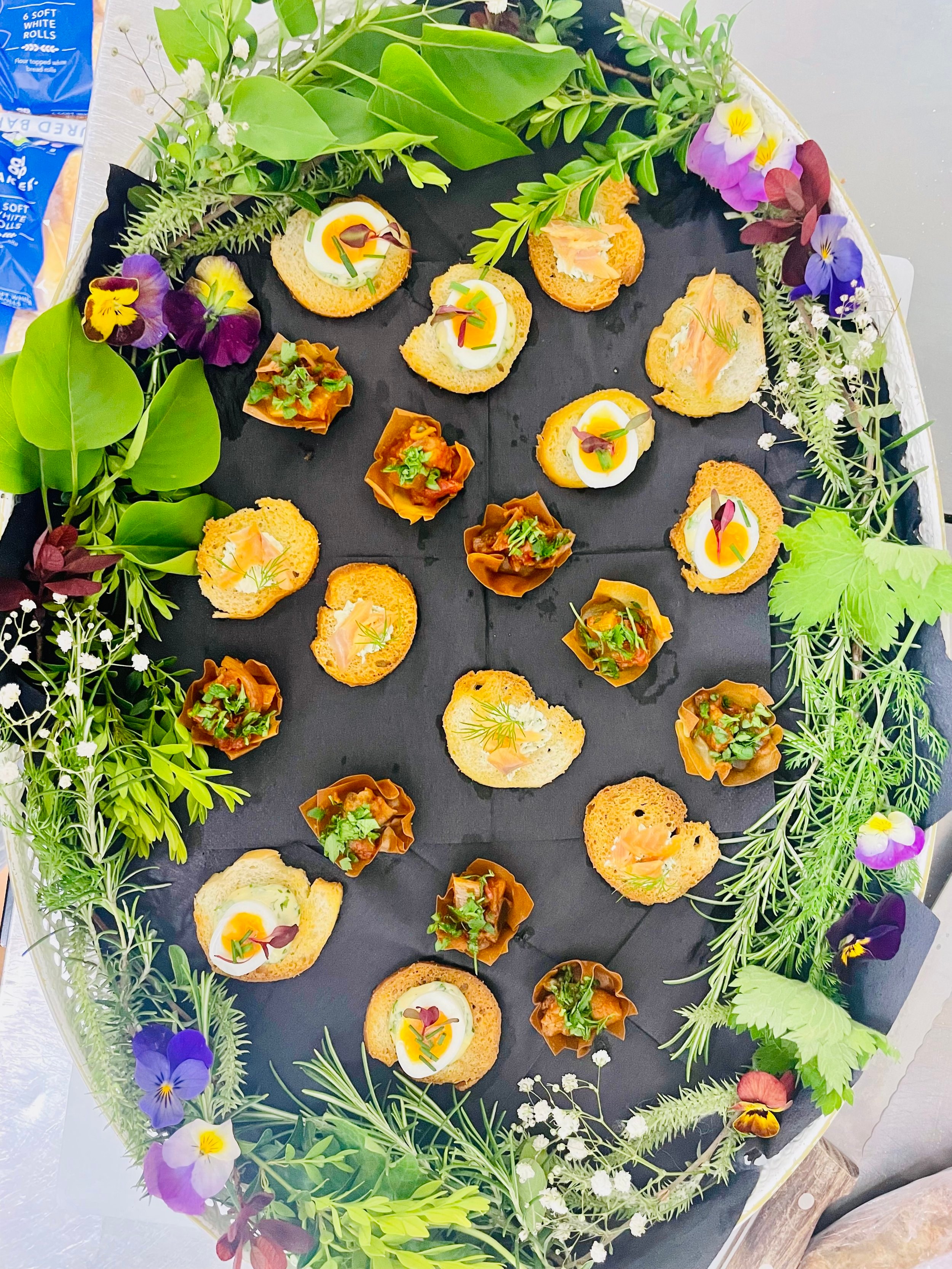Canapés on a slate platter with edible flowers