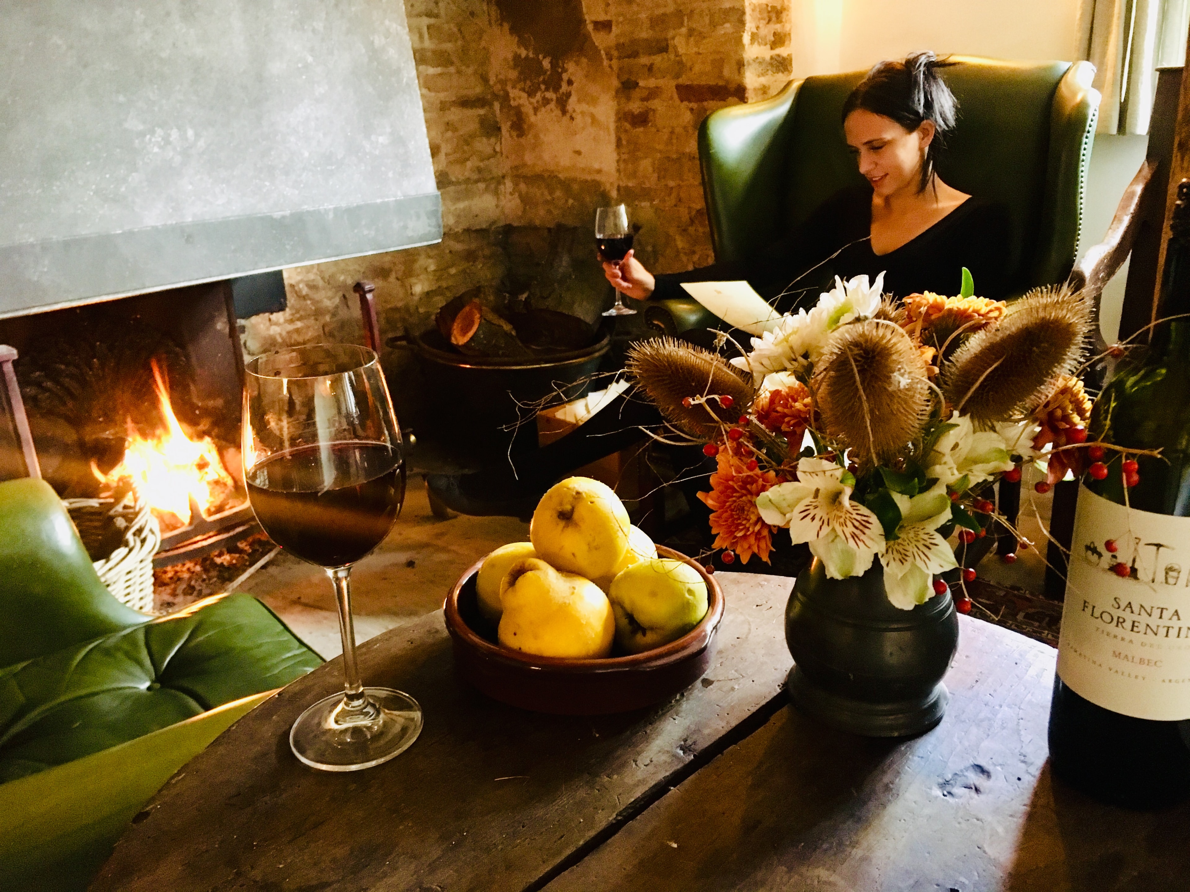 Guest relaxing by the inglenook fireplace with a glass of wine